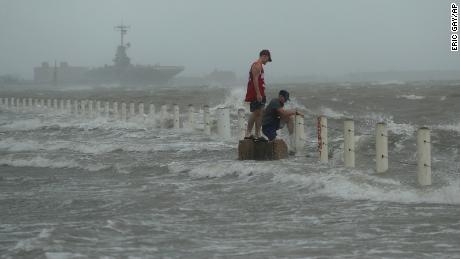 Two men stand near a sea wall as Hurricane Hanna makes landfall.