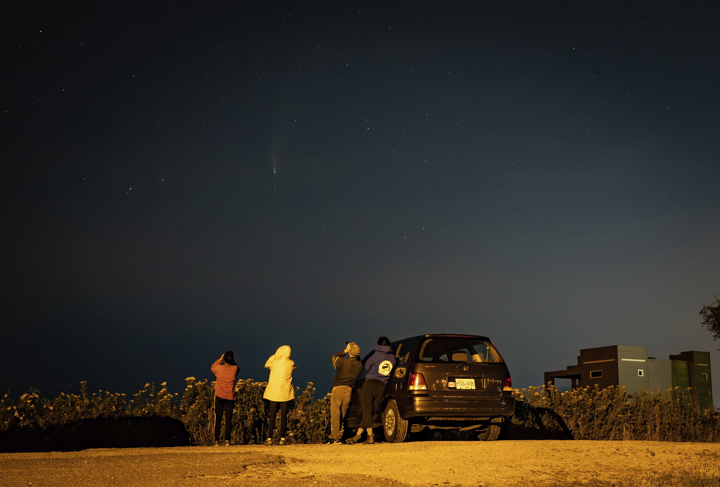 People use binoculars to view the comet Neowise as it appears in the night sky, in Delta, B.C., Monday, July 20, 2020. (Darryl Dyck/The Canadian Press via AP)