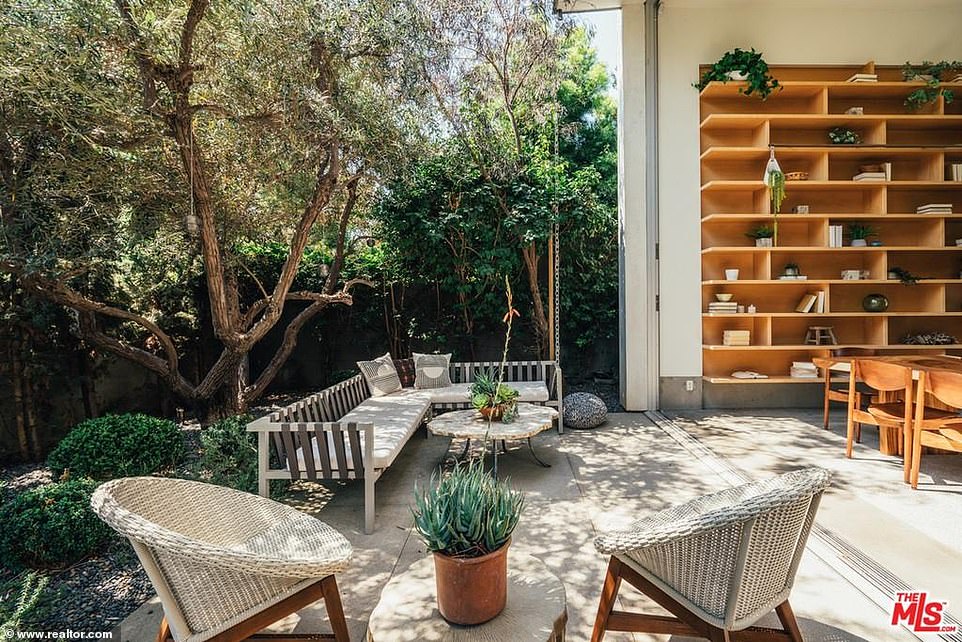 An indoor/outdoor California style: The living room opens up to a small but stylish outdoor area with mature trees