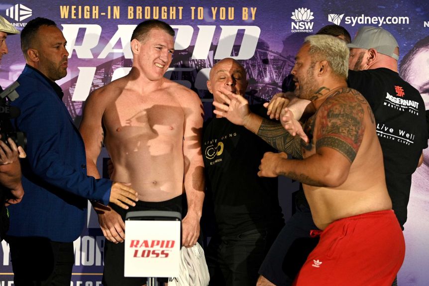 Paul Glenn smiles at Mark Hunt as he is held back by mindful thinkers before the boxing match.