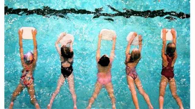The picture above shows five children in a swimming class using a board