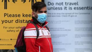 Man standing in a London bus stop wearing a face mask