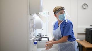 A nurse in PPE washing her hands at a primary care centre in Grimsby.