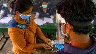 An election official sprays disinfectant on a voter during a mock election in Sri Lanka, 14 June 2020