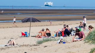 People relax on Crosby Beach on the Merseyside
