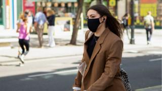 A woman wearing a mask walks down Oxford Street