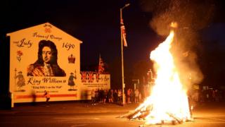 A bonfire burning in front of a William of Orange Mural