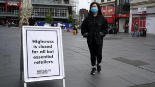 A woman stands next to a sign reading 