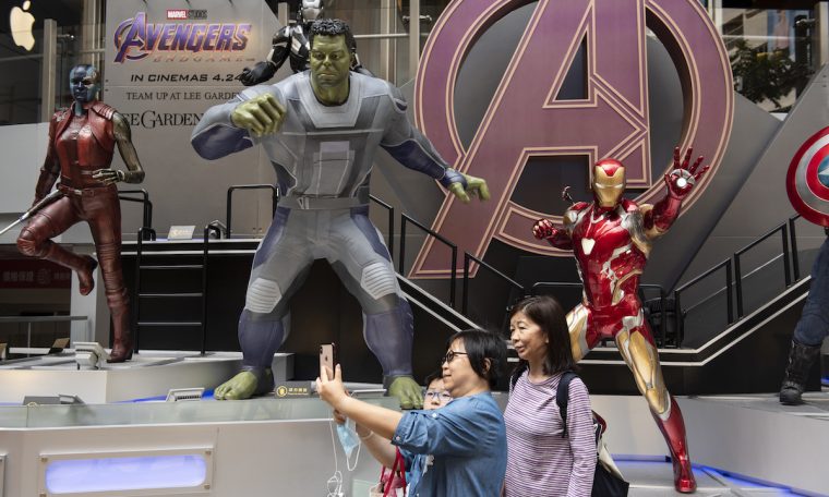 Pedestrians taking a selfie with Marvel figures