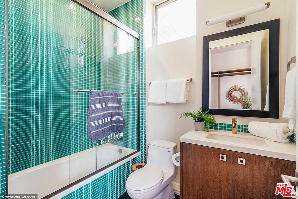 Small but sensible: And the second bathroom includes a green tiled shower next to a single sink vanity