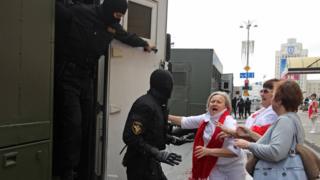 A police officer detains Belarusian opposition supporters ahead of a march in Independence Avenue, 30 August