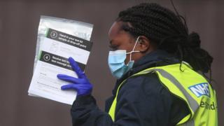 An NHS test and trace worker maintains self-examination kits at a testing center in Bolton