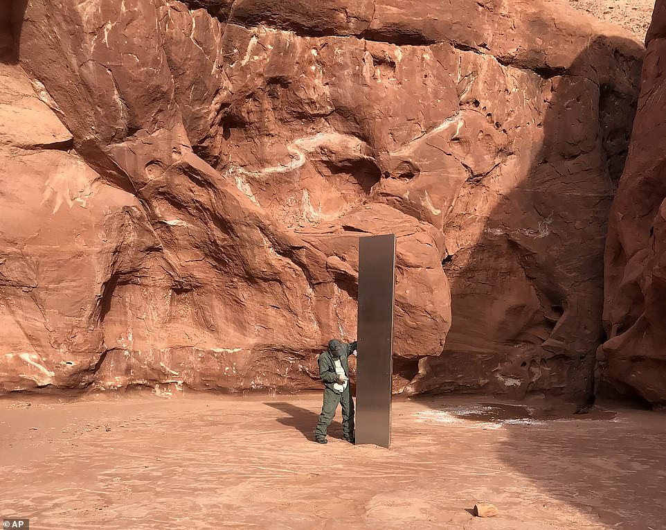 A picture provided by the Utah Department of Public Safety shows a state employee inspecting a mysterious metal monolith found earlier this week in a remote area of ​​the Red Rock Desert. .