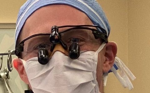 A surgeon demonstrates how to use a band-aid to prevent fogging glass masks