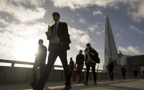 Commuters cross London Bridge in view of The Shard in London on November 2 ahead of a partial lockdown in UK.