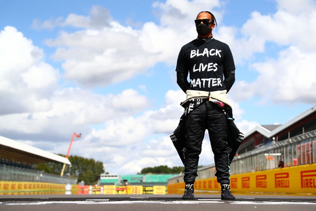 Northampton, England - August 02: Lewis Hamilton of Great Britain and Mercedes GP is wearing a T-shirt displaying the message 'Black Lives Matter' as he heads off the grid in support of the movement to end racism before the Formula One British Standing in front.  Gray (Photo: Formula 1 via Getty Image)