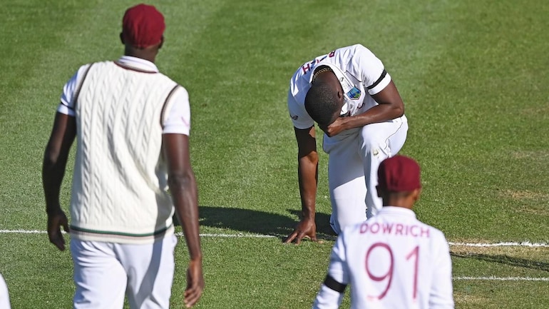 West Indies pacer Kemar Roach kneels after taking the wicket of Tom Latham