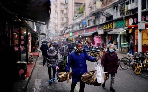 People wearing protective masks walk at a street market almost a year after the start of the coronavirus disease (Covid-19) outbreak, in Wuhan, Hubei province, China.