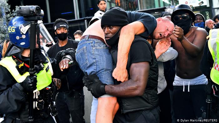 A black man carrying a white person in a crowd