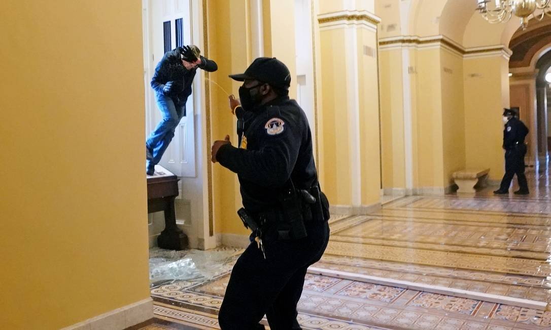 A Capitol police officer throws pepper spray at a guard who tries to enter the Congress building Photo: POOL / REUTERS