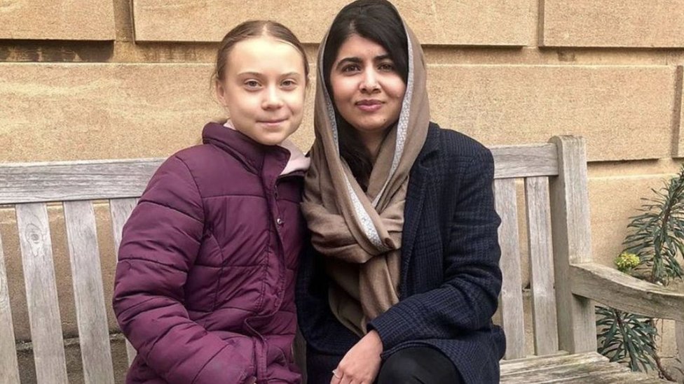 Greta and Malala photographed sitting on the bench