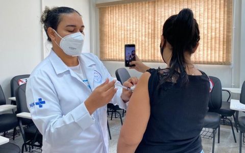Mulher tira selfie enquanto é vacinada