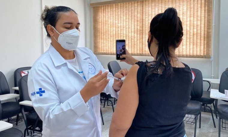 Mulher tira selfie enquanto é vacinada