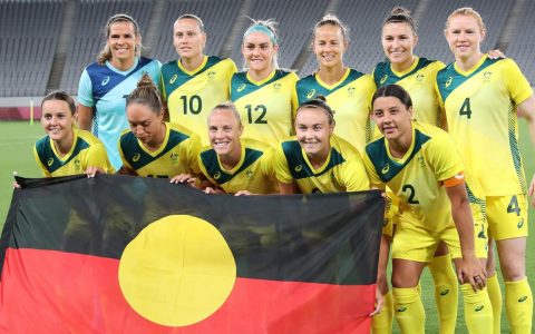 Seleção de futebol feminino da Austrália segura a bandeira aborígene