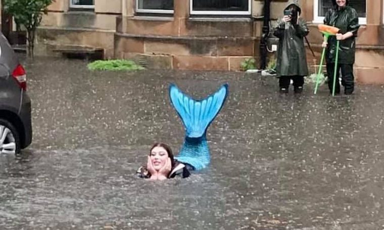 A woman dressed as a mermaid is photographed in the middle of the floods in Scotland.  World