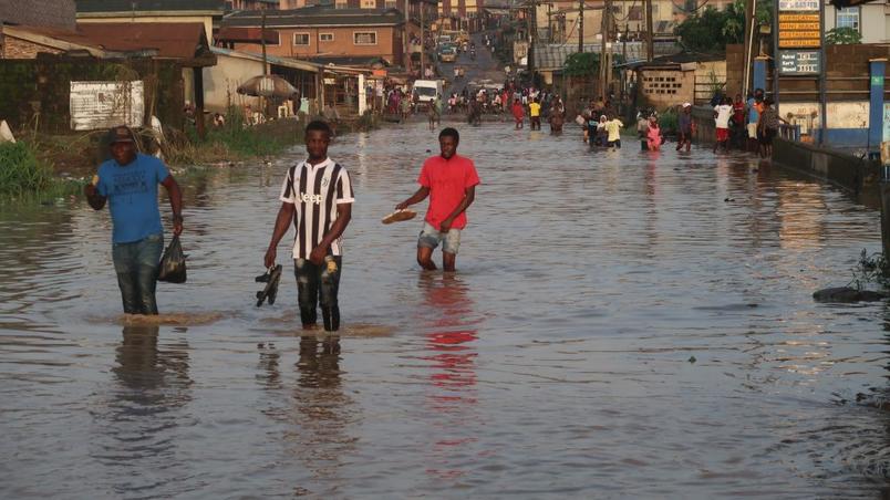 6.  Residents walk along a flooded road in Aboru, Lagos, after heavy rain in the