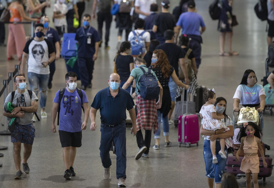 Passengers walk into the passenger terminal at Guarulhos International Airport in Guarulhos, near Sao Paulo, Brazil, on Wednesday, December 30, 2020, amid the COVID-19 pandemic.  Despite the rising number of infections in the country, Brazilians are flocking to airports and highways to start the new year and take advantage of a long weekend to meet friends and loved ones.  (AP Photo/Andre Penner)